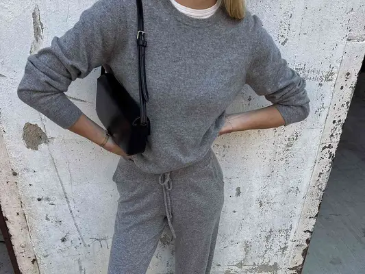 Close-up of woman wearing gray matching knitwear set and black shoulder bag