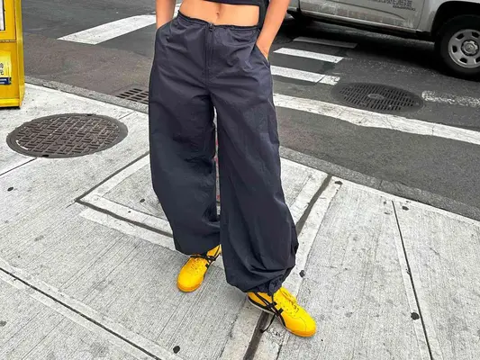 Close-up of Rita Ora wearing baggy pants and yellow and black Onitsuka Tiger Mexico 66 sneakers