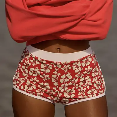 Woman wears navy bikini top, swim skirt, and bellybutton piercing jewelry