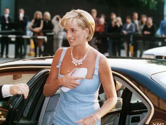 Princess Diana wears a blue Jacques Azagury shift dress and carries a satin clutch