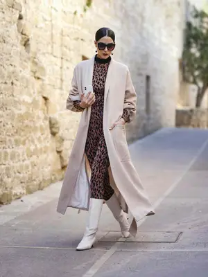Model Zoe Helali wearing a beige coat by Sasha La Mer, a brown and black leopard print longsleeve shirt and matching leggings by Wolford, vintage white boots, silver and black earrings by silverelephant and sunglasses by CJ 
