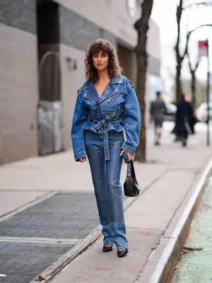 Woman wearing denim moto jacket, embellished jeans, black shoes, and bag