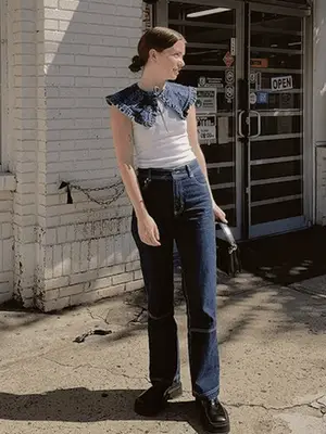 Mecca James-Williams wears a denim bra, patterned blue shirt dress worn open, jeans with frayed hem, and white open-toed mules