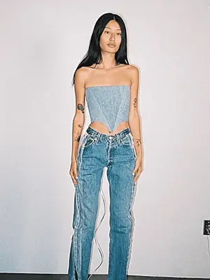 Abby Bible wears a dark wash denim jacket, jeans, vintage brown shoulder bag, and red tinted lens sunglasses