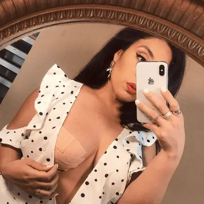 A woman wearing boob tape under a polka-dotted wrap dress