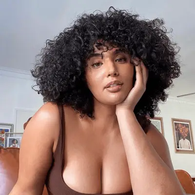 Woman wearing neutral breast tape and gold hoop earrings