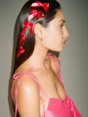 Woman wearing several red hair ribbons and a pink dress with bow straps