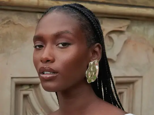 Model wearing gold sculptural earring