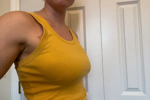 A person wears Nue Breast Tape under a tank top