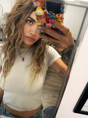 Rita Ora taking phone mirror selfie wearing purple crystal necklace