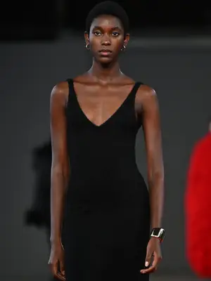 model walking down runway wearing black dress and oversized metal arm bangle cuff