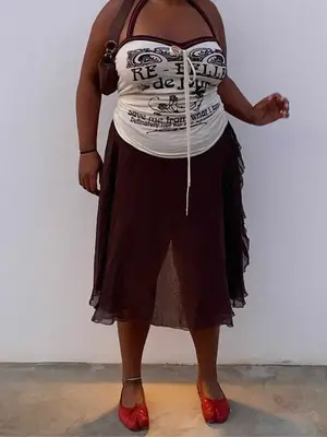 Paloma Elsesser wearing a printed tube top, brown skirt, red tabi flats, and brown shoulder bag