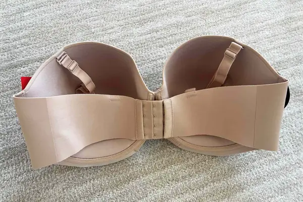 Back of the Spanx Up For Anything Strapless Bra displayed on a beige surface
