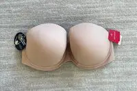 Spanx Up For Anything Strapless Bra with tags displayed on a beige carpet background 