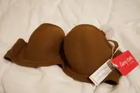 Curvy Kate Luxe Strapless Bra with tags displayed on a white comforter