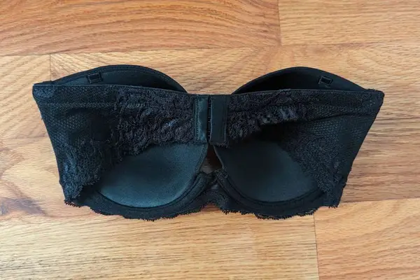 Back of the Natori Feathers Strapless Bra displayed on a wooden floor 