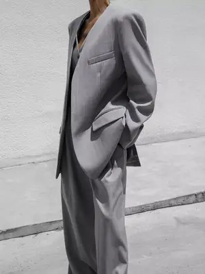 Model wearing gray three-piece suit with concrete background