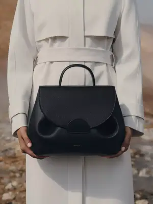Close-up of person wearing white coat and carrying black Polene handbag