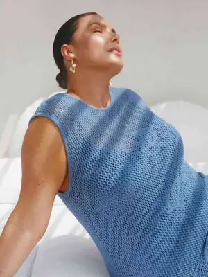 Model wearing a blue crochet top and statement earrings while lounging