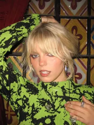 Renee Rapp wearing a neon green and black top and silver jewelry