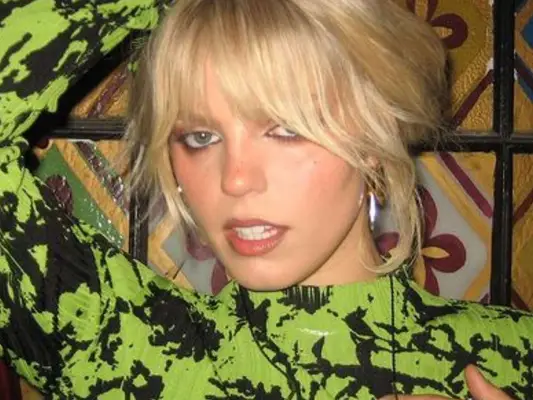 Renee Rapp wears a green and black top and silver earrings