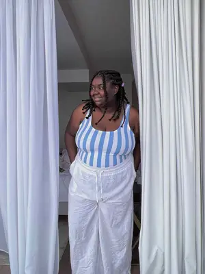 Abisola Omole wears a blue and white striped bodysuit and white linen pants
