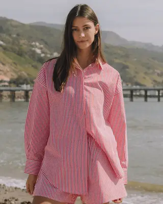 Close-up of woman wearing white bikini top and blue striped button-down shirt and shorts