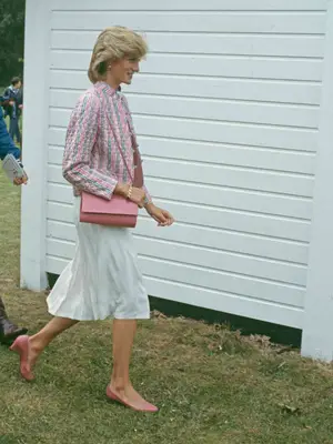 Princess Diana wears a pink crossbody bag, pink kitten heels, white skirt, and pink patterned blazer