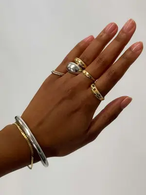 Close-up of person wearing stacked gold and silver bracelets and rings