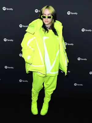 Billie Eilish wears a lime green Valentino sweatsuit, coat, and sneakers to the Spotify Best New Artist 2020 Party