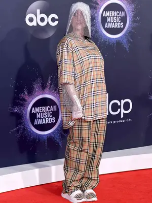 Billie Eilish wears a plaid Burberry pants set with bedazzled veil, sleeves, and plaid sneakers