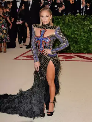 Jennifer Lopez wears a Balmain gown with feathered skirt and cross detail to the 2018 Met Gala