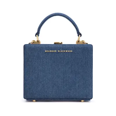 Back view of woman wearing white top with draped tie and long denim shorts