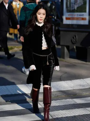 person wearing a black cardigan, lace top, velvet Bermuda shorts, and dark red boots