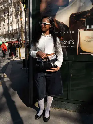 Person wears a white button-down, dark wash Bermuda shorts, and white lace tights