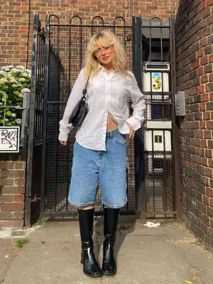 Woman wearing button-down shirt, tailored Bermuda shorts, and leather handbag with chain strap