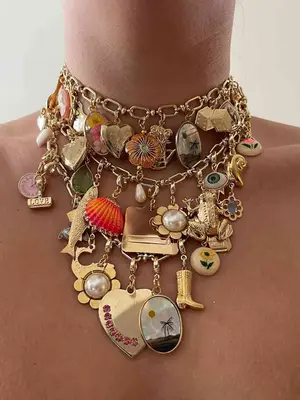 Close-up of several charm necklaces with flower, fish, shell, heart, etc charms on model
