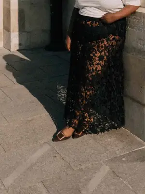 Close-up of Abisola Omole wearing black lace maxi skirt, white t-shirt, and buckled flats