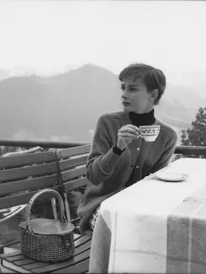 Audrey Hepburn wearing a cardigan and a black turtleneck while holding a teacup