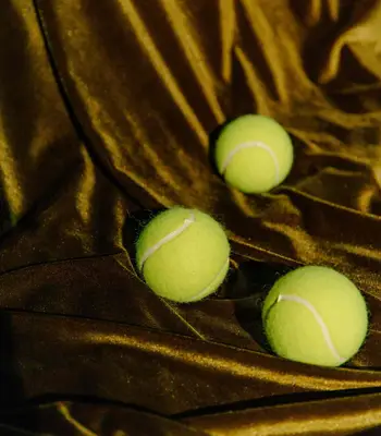 Three tennis balls on gold fabric background