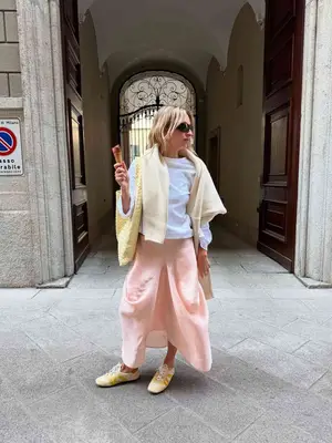 Izzi wears a white tee, pink skirt, yellow sweater and yellow sneakers