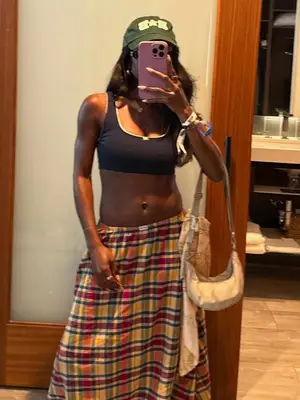 Toni Bravo wearing a navy sports bra top, plaid skirt and green hat