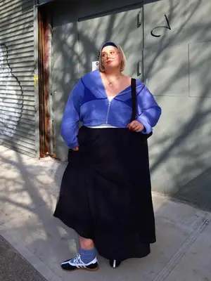 Abby Bible wears a black skirt, white top, purple jacket, and headband