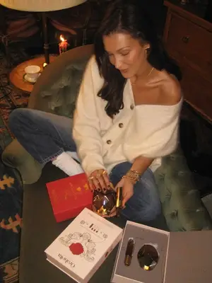 Bella Hadid wearing a cream button-down cardigan off the shoulder