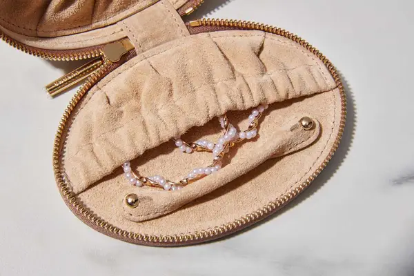 Close-up of jewelry sticking out of a Cuyana Travel Jewelry Case