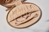 Close-up of jewelry sticking out of a Cuyana Travel Jewelry Case