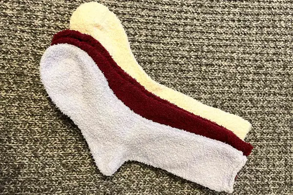 a pack of white, red, and yellow Bombas Fuzzy Socks on carpet