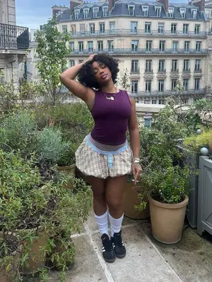 SZA wearing a purple top, plaid bubble shorts and black sneakers