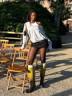 model wears a tank top, jacket, black bloomers and yellow boots