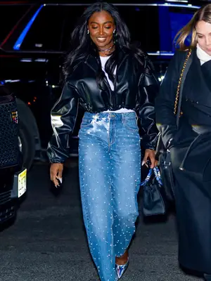 Patina Miller wears a leather bomber jacket, bedazzled jeans, black handbag, and iridescent pumps